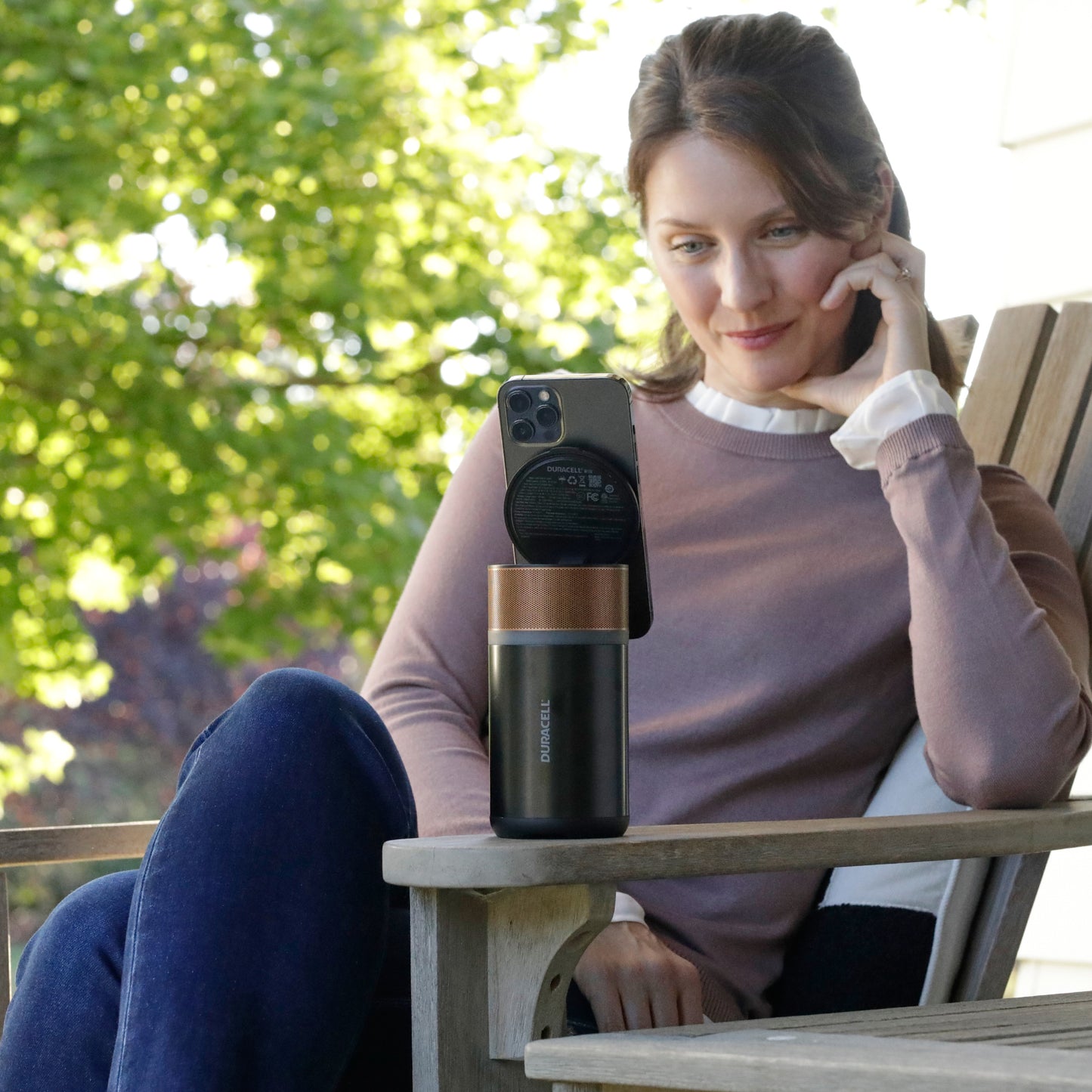 Woman on her patio using the M150 charger outside to hold and charge her smartphone