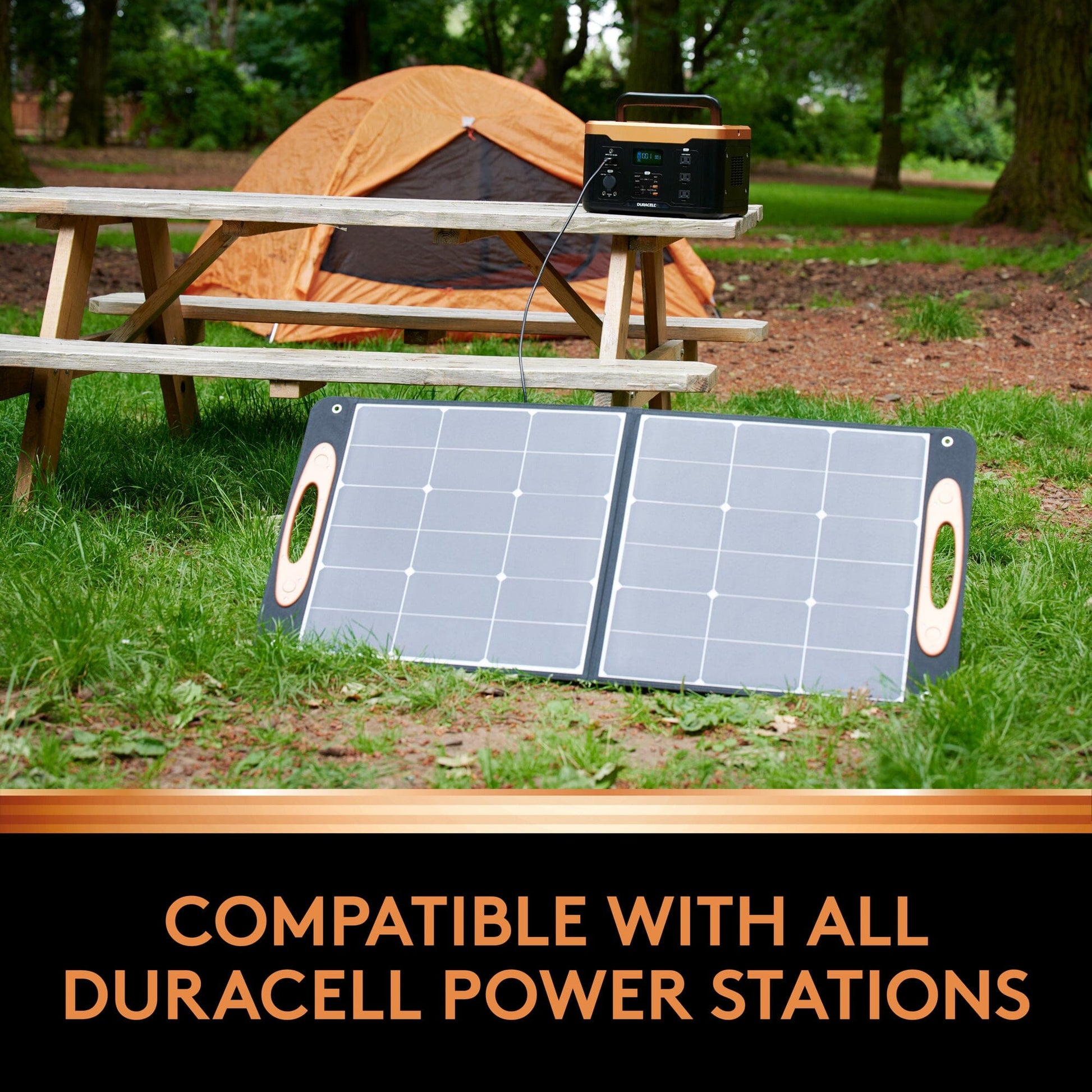 Image of a solar panel in the grass by a picnic table and a tent.